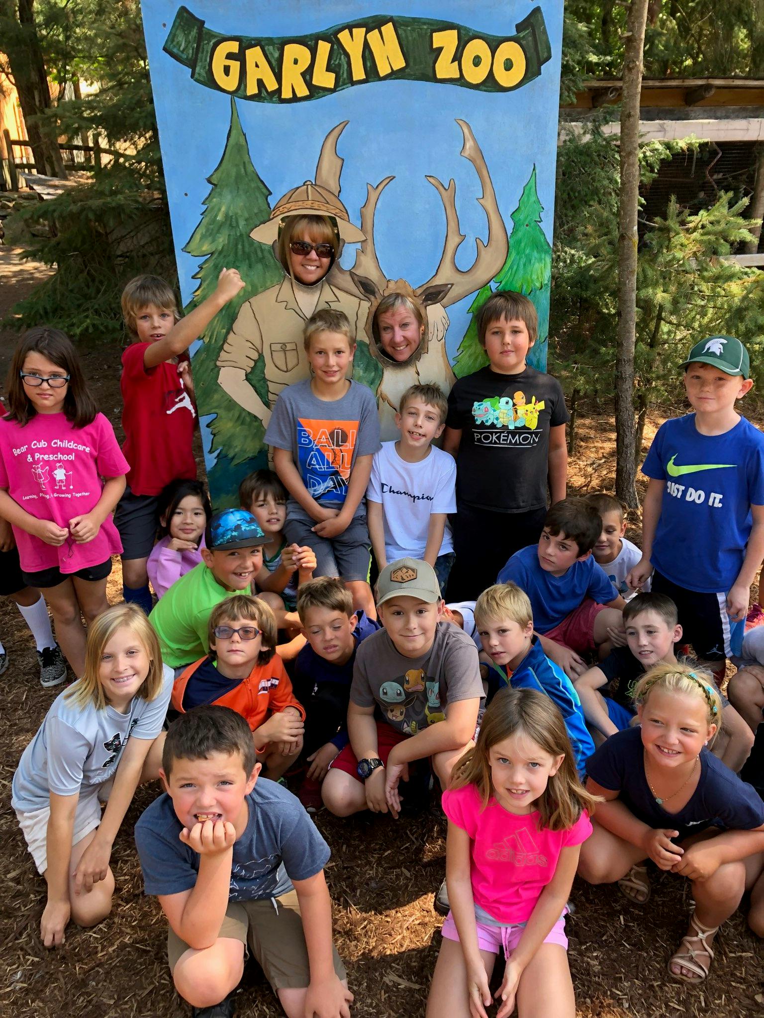 Group of children and adults posing in front of a Garlyn Zoo sign