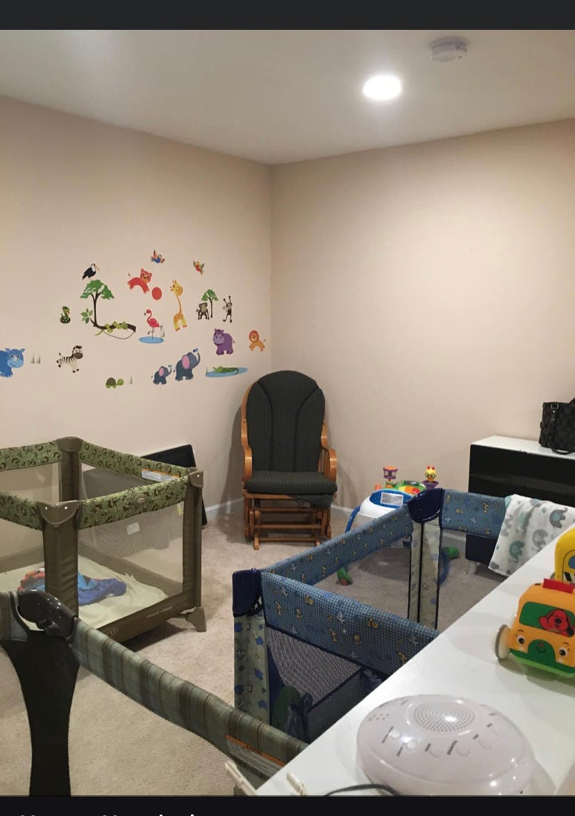 Two playpens and a rocking chair in a room with animal wall decals