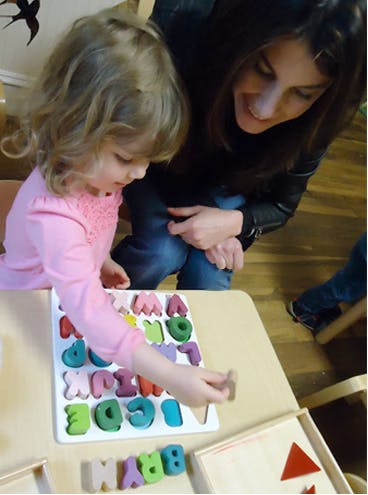Child and person playing with an alphabet puzzle