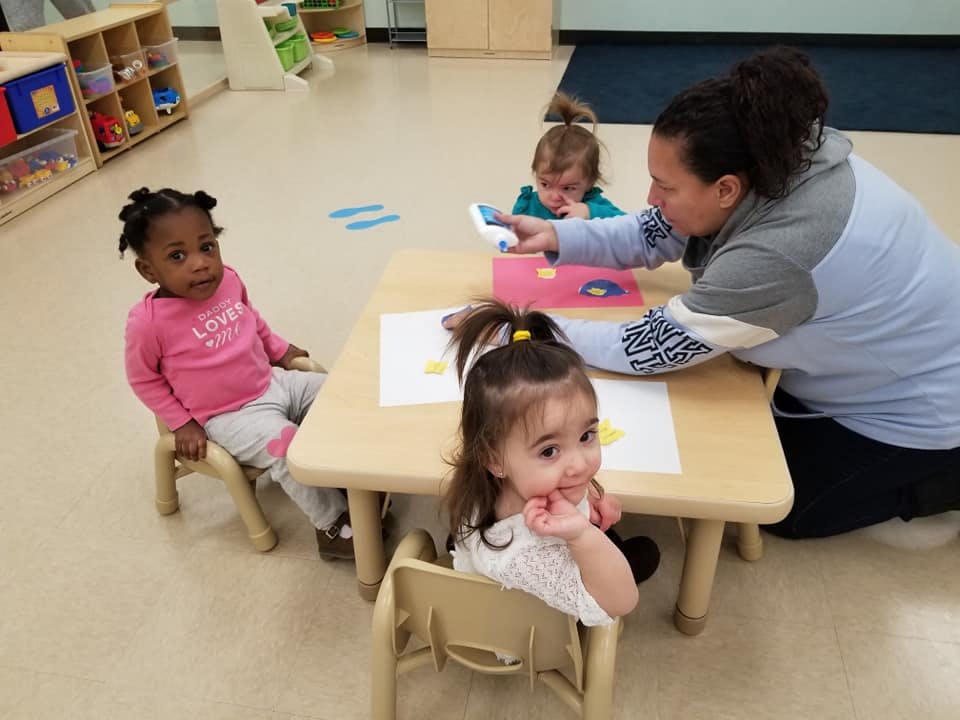 Adult and three children at a small table in a classroom