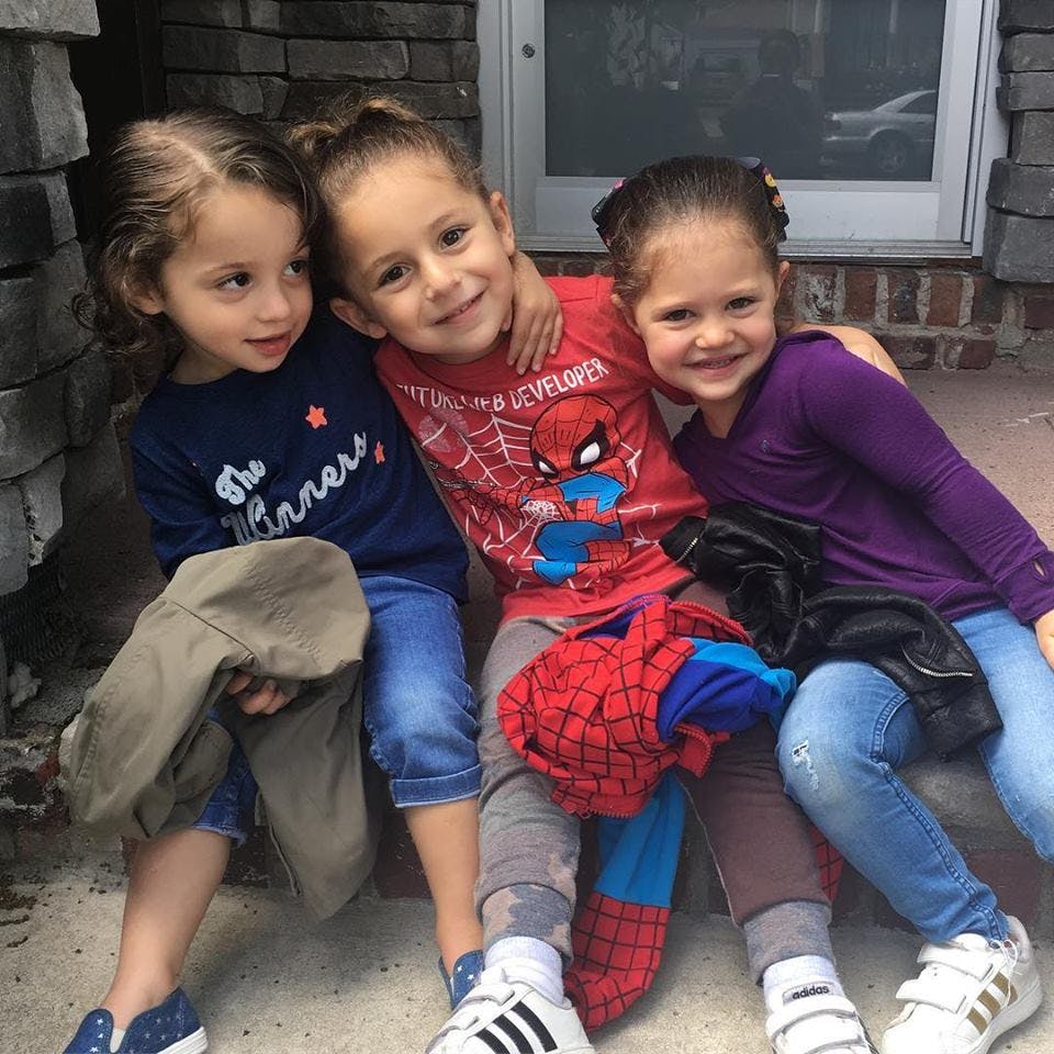 Three children sitting together, one with arm around another