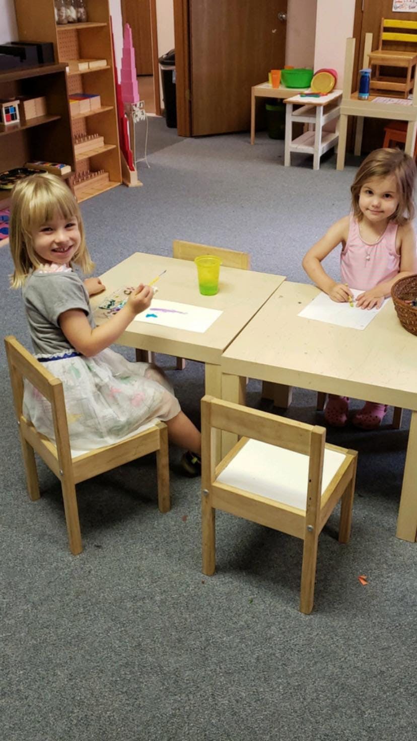 Two children sitting at tables in a classroom