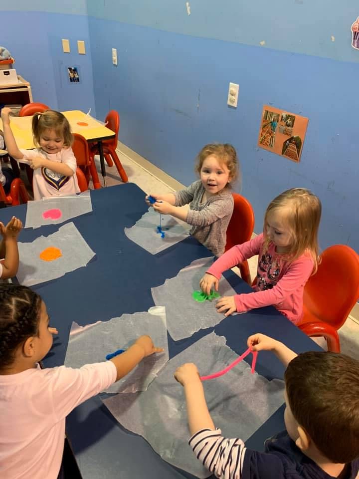 Children sitting at a table doing an art activity