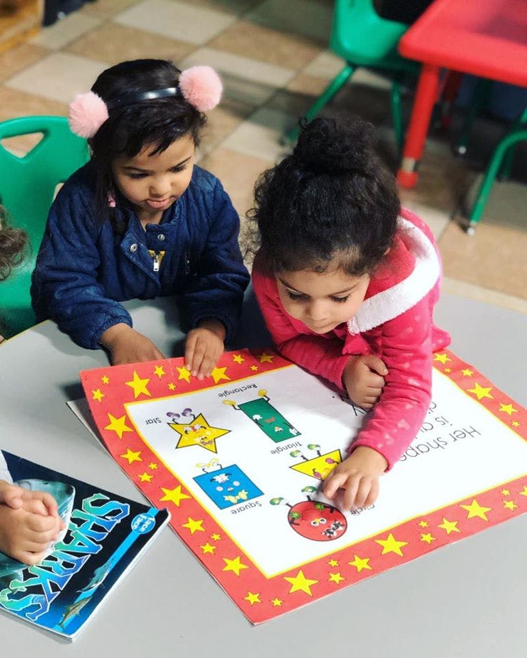 Two children looking at a shapes chart