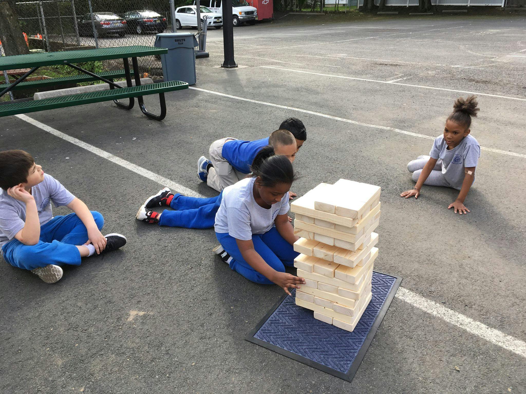 Children playing with a large block-stacking game outdoors