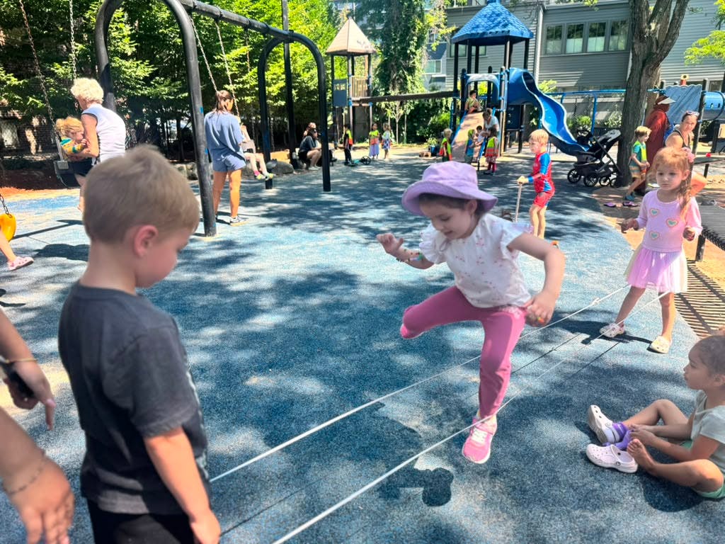 Child jumping over a rope at a playground
