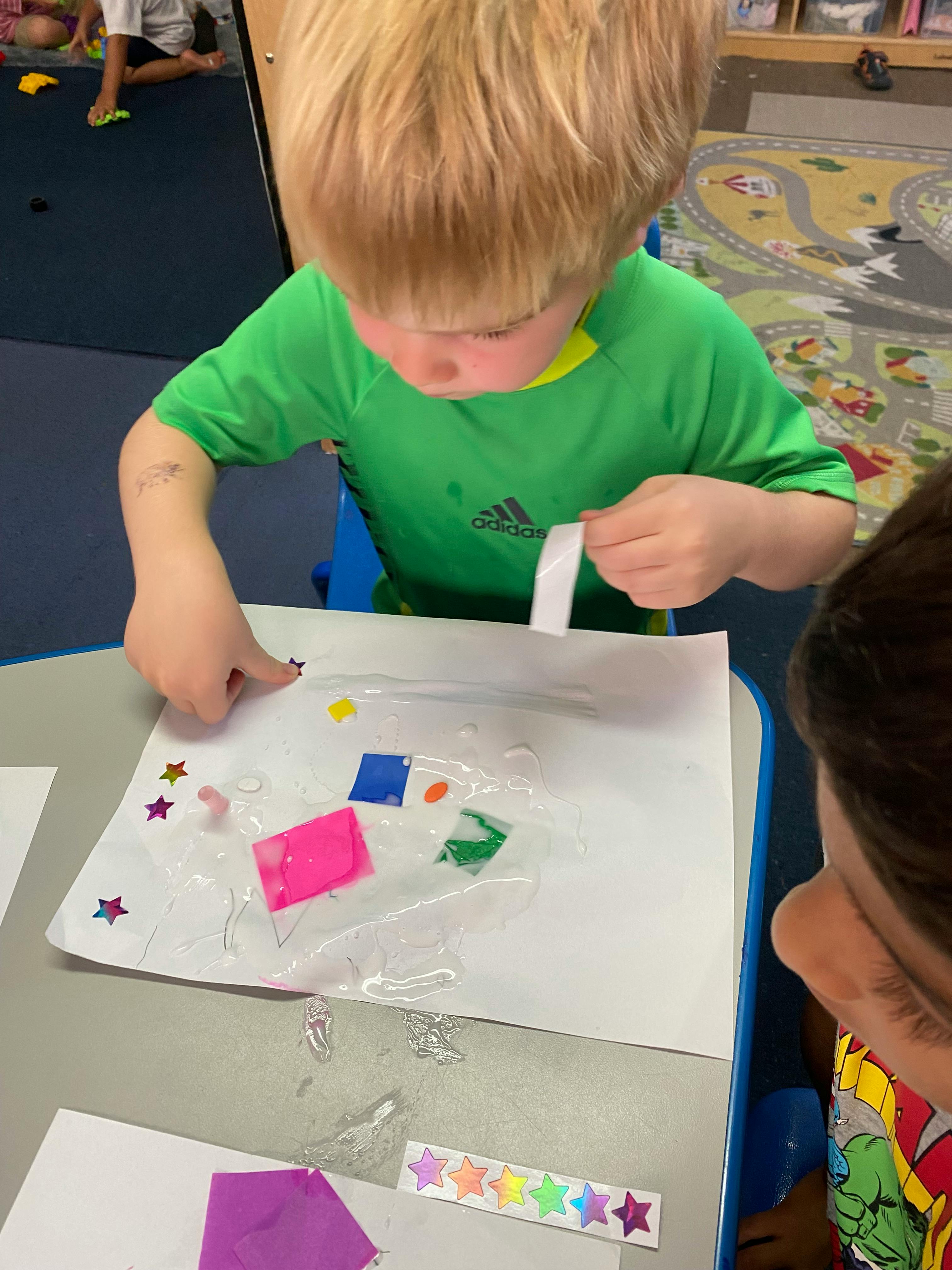 Child creating art with paper and stickers at a table