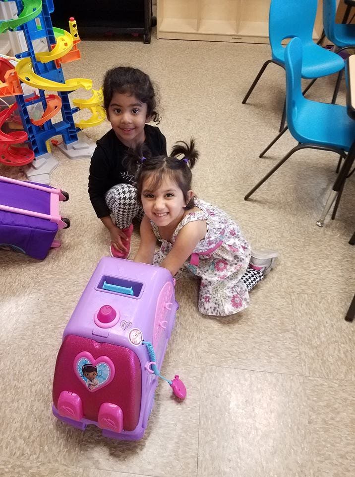 Two children playing with a toy on the floor