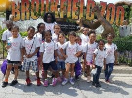 Group of children standing in front of a sign that says "BROOKFIELD ZOO"