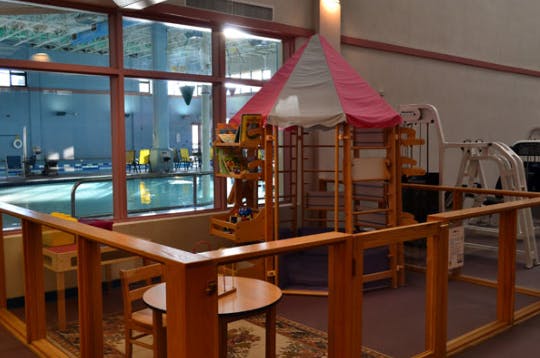 Indoor play area with a tent and a view of a swimming pool through a window