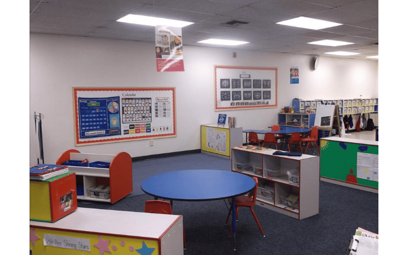 Empty classroom with a blue round table and red chairs