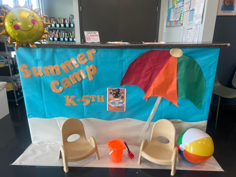 Summer Camp K-5th sign with beach umbrella, chairs, and beach ball