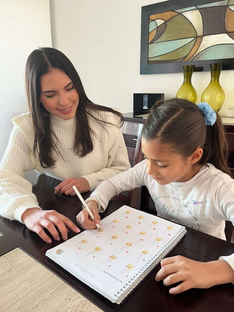 Person and child writing in a notebook at a table
