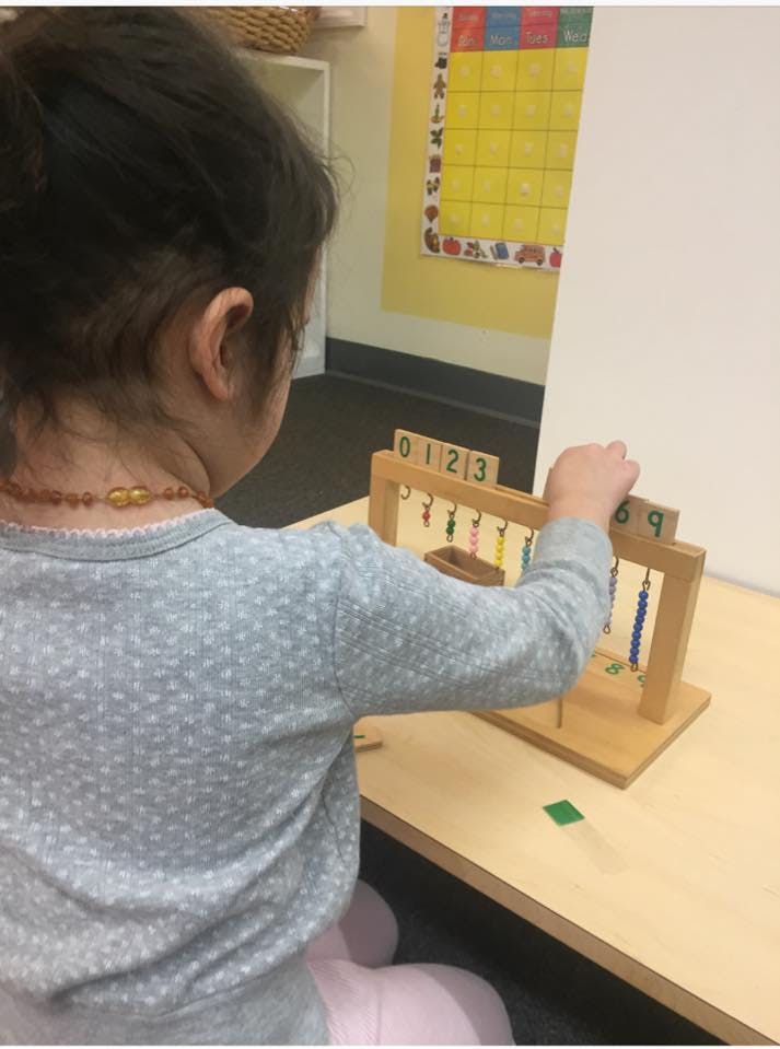 Child playing with a wooden counting frame with beads