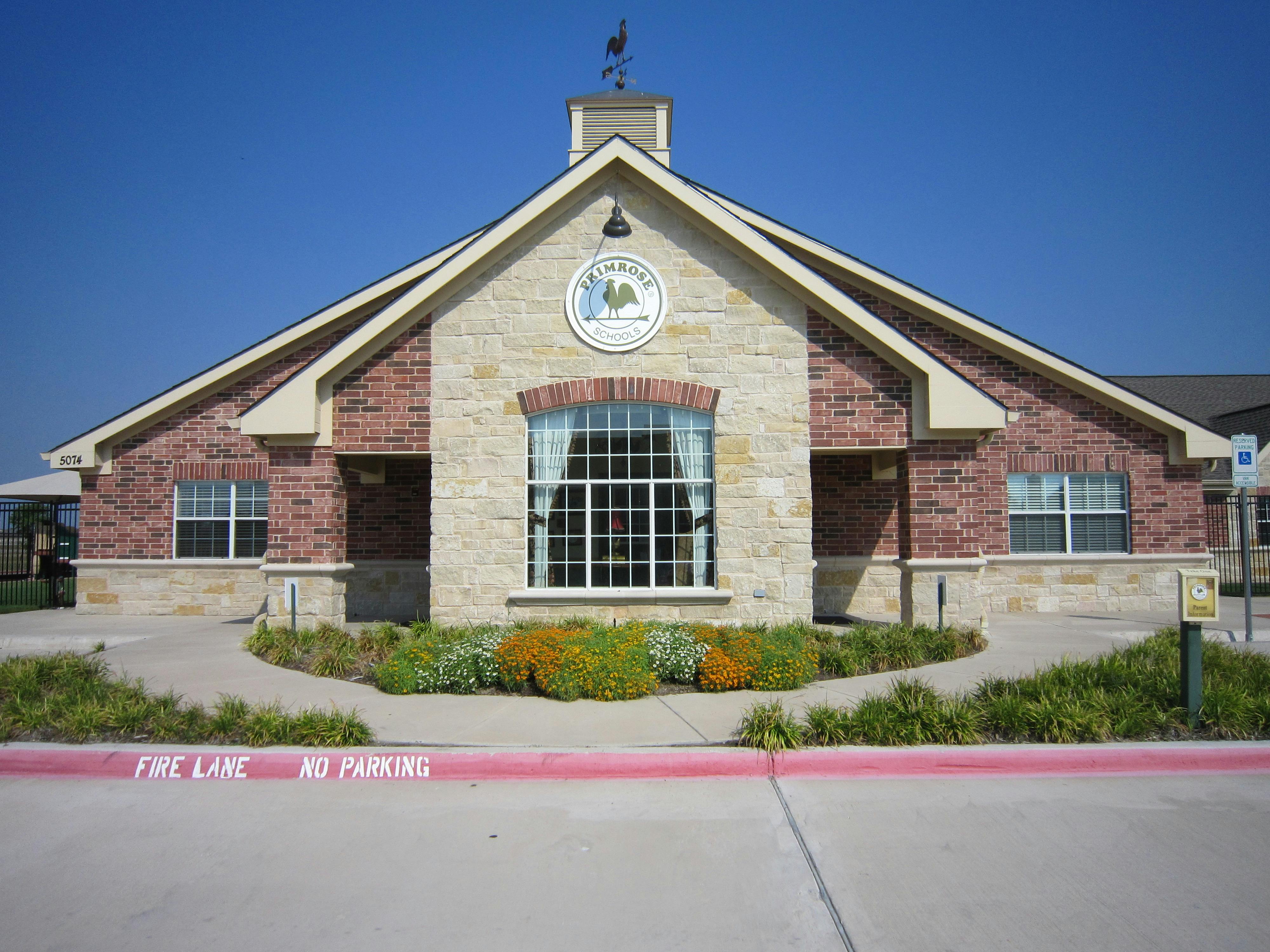 Building with brick and stone facade, large arched window, and a weather vane