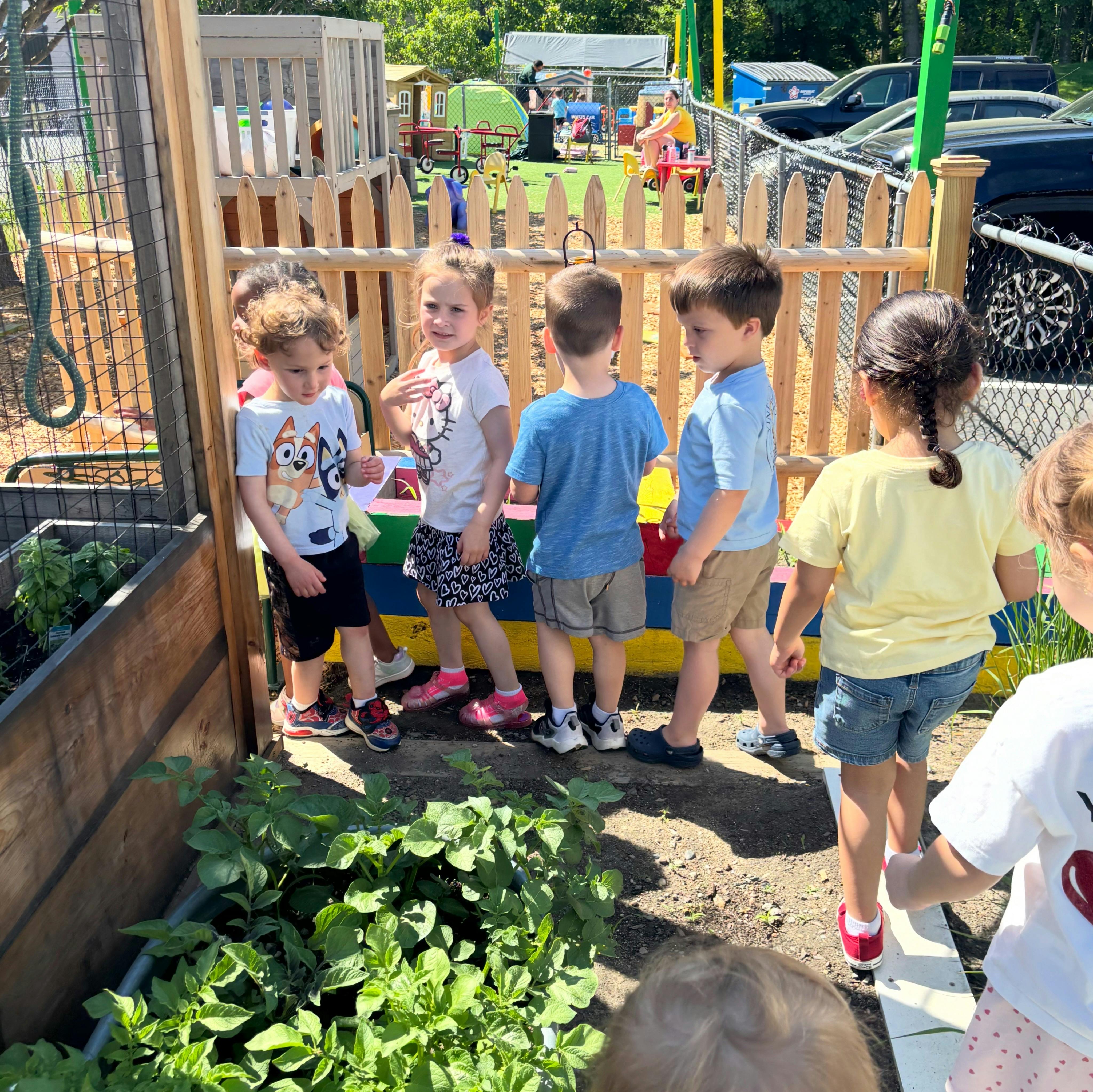 Group of children standing near a raised garden bed at a playground