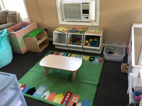 Playroom with a small table on a rug, toy storage, and an air conditioner