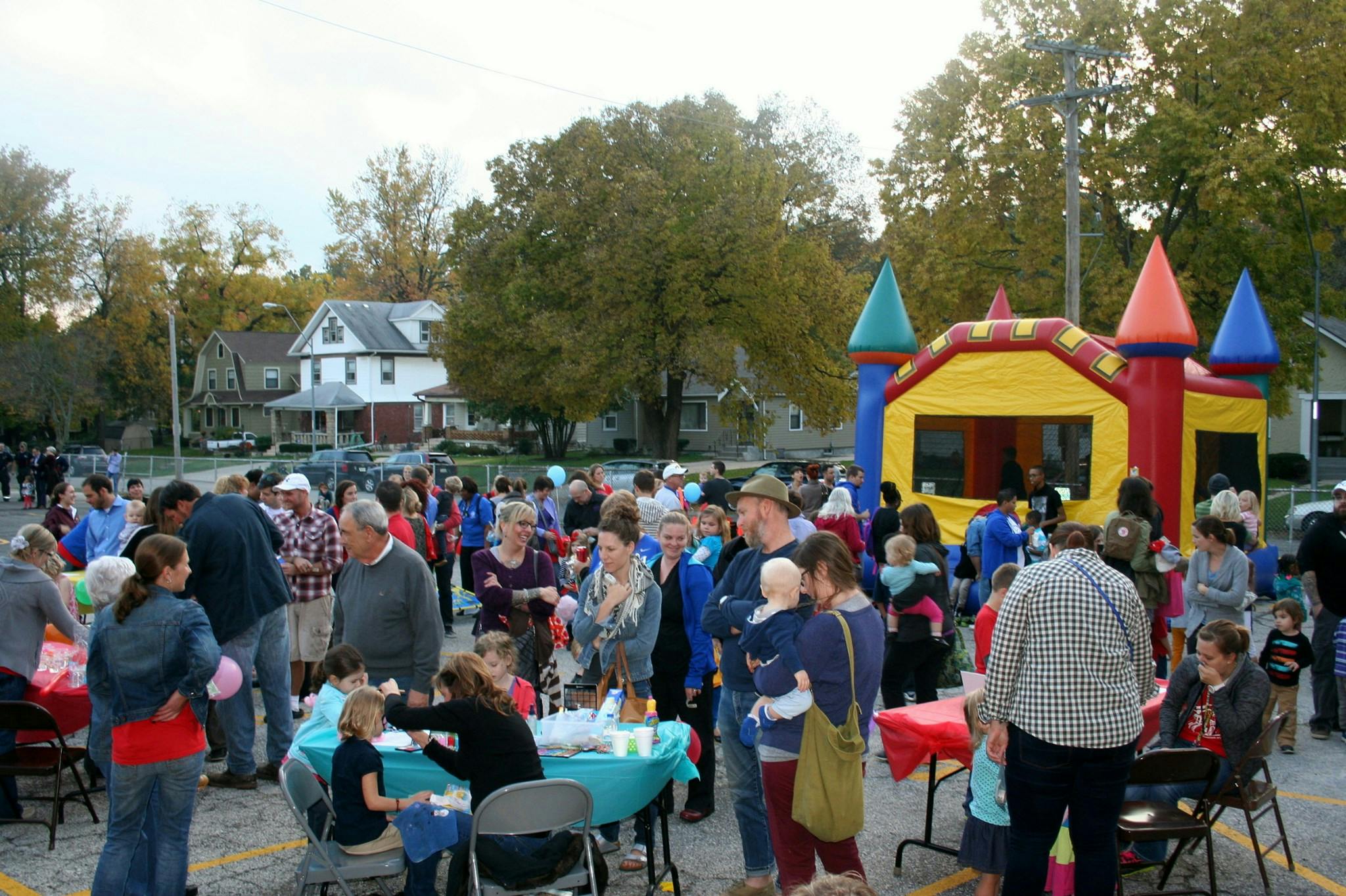 Crowd of people gathered outdoors with a bounce house in the background