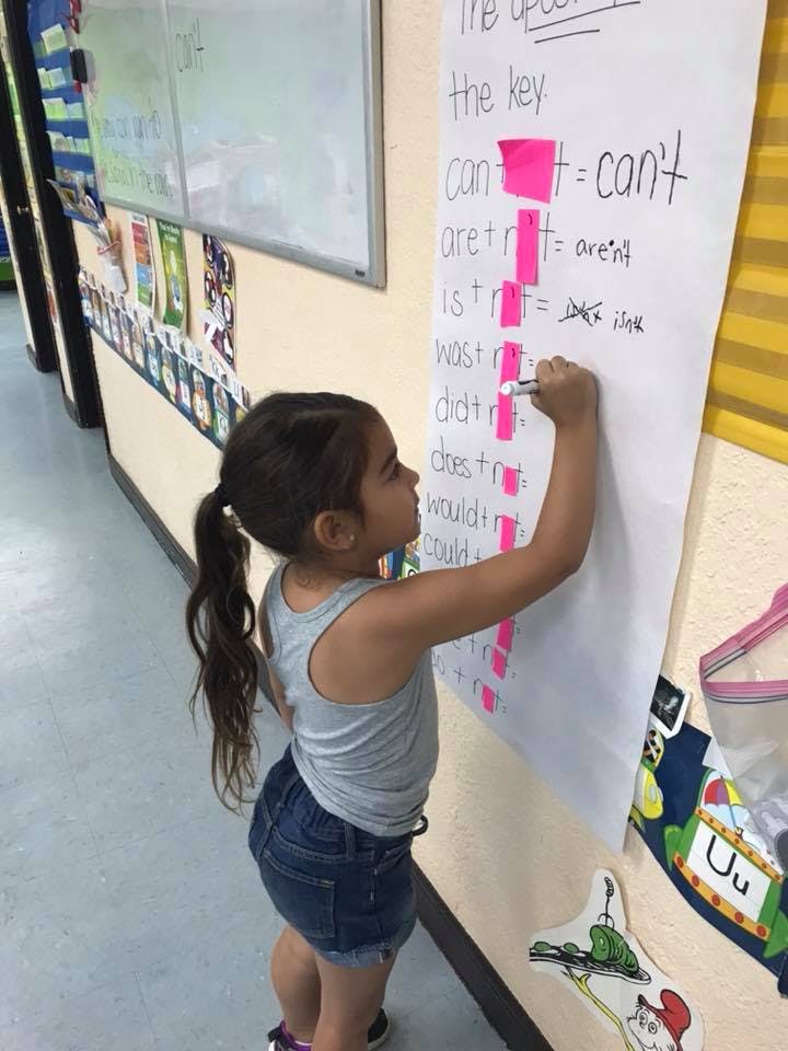 Child writing on a large paper chart in a classroom