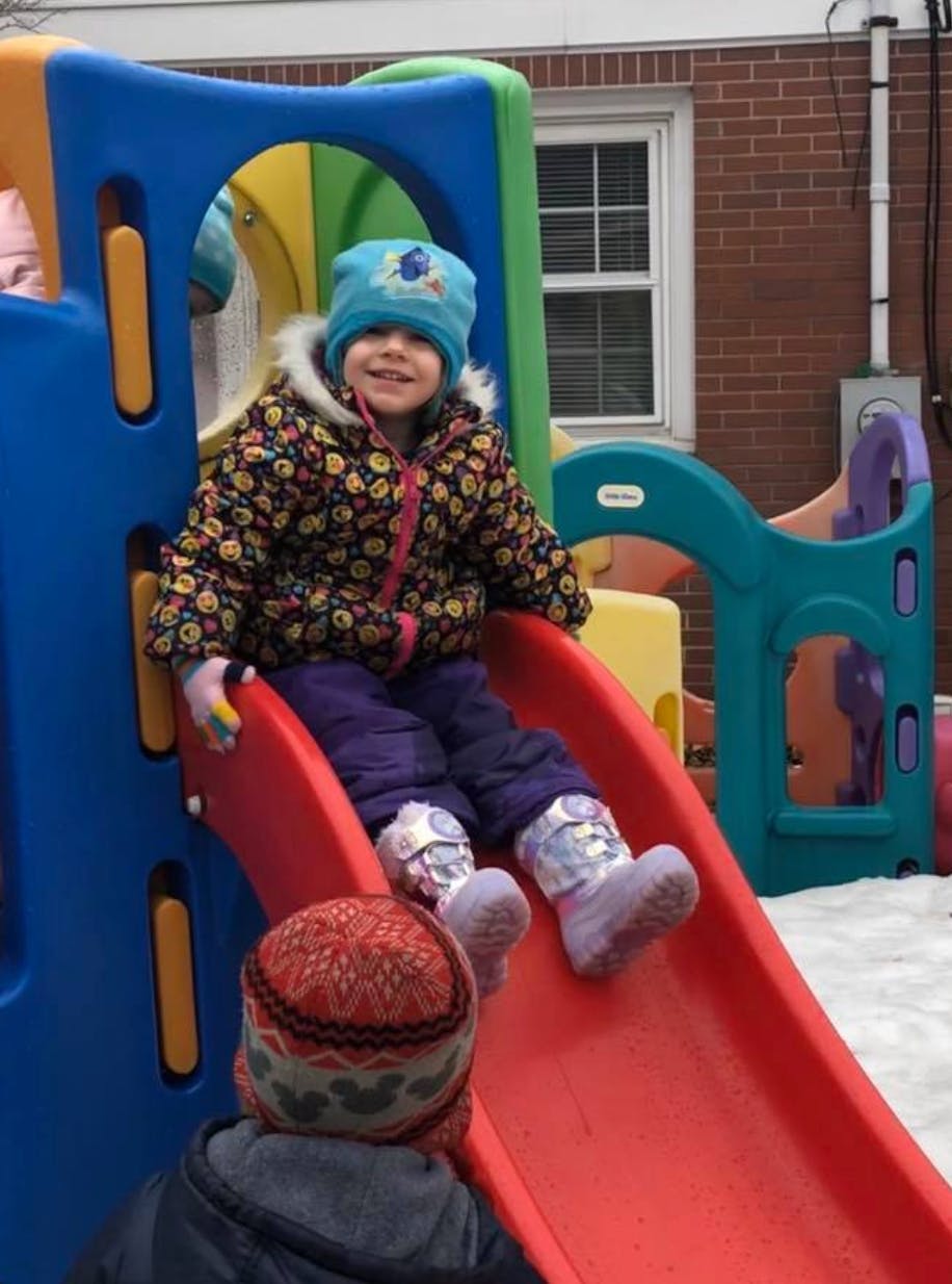 Child in winter clothing on a red slide