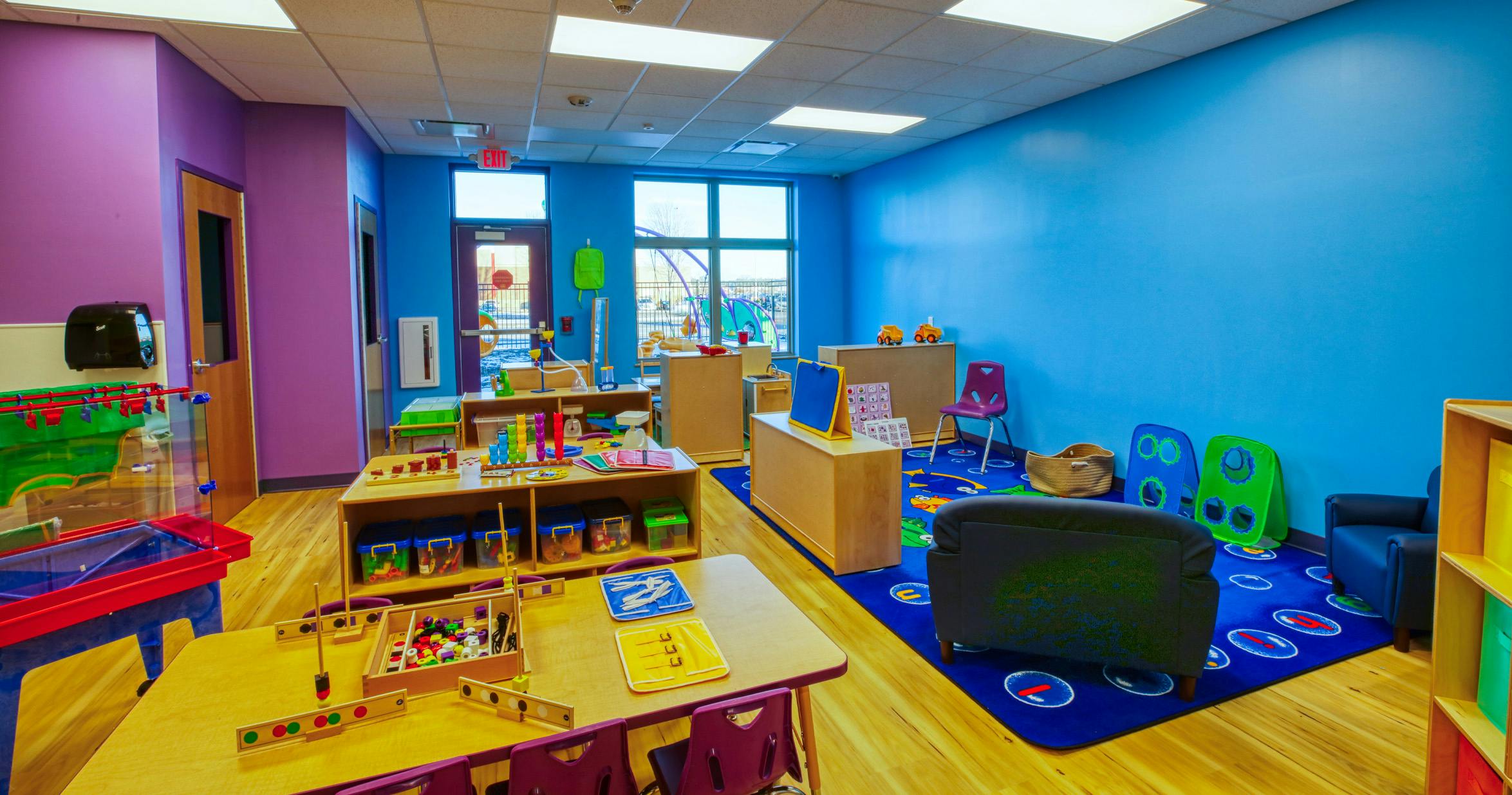 Colorful classroom with various toys, tables, and a blue rug