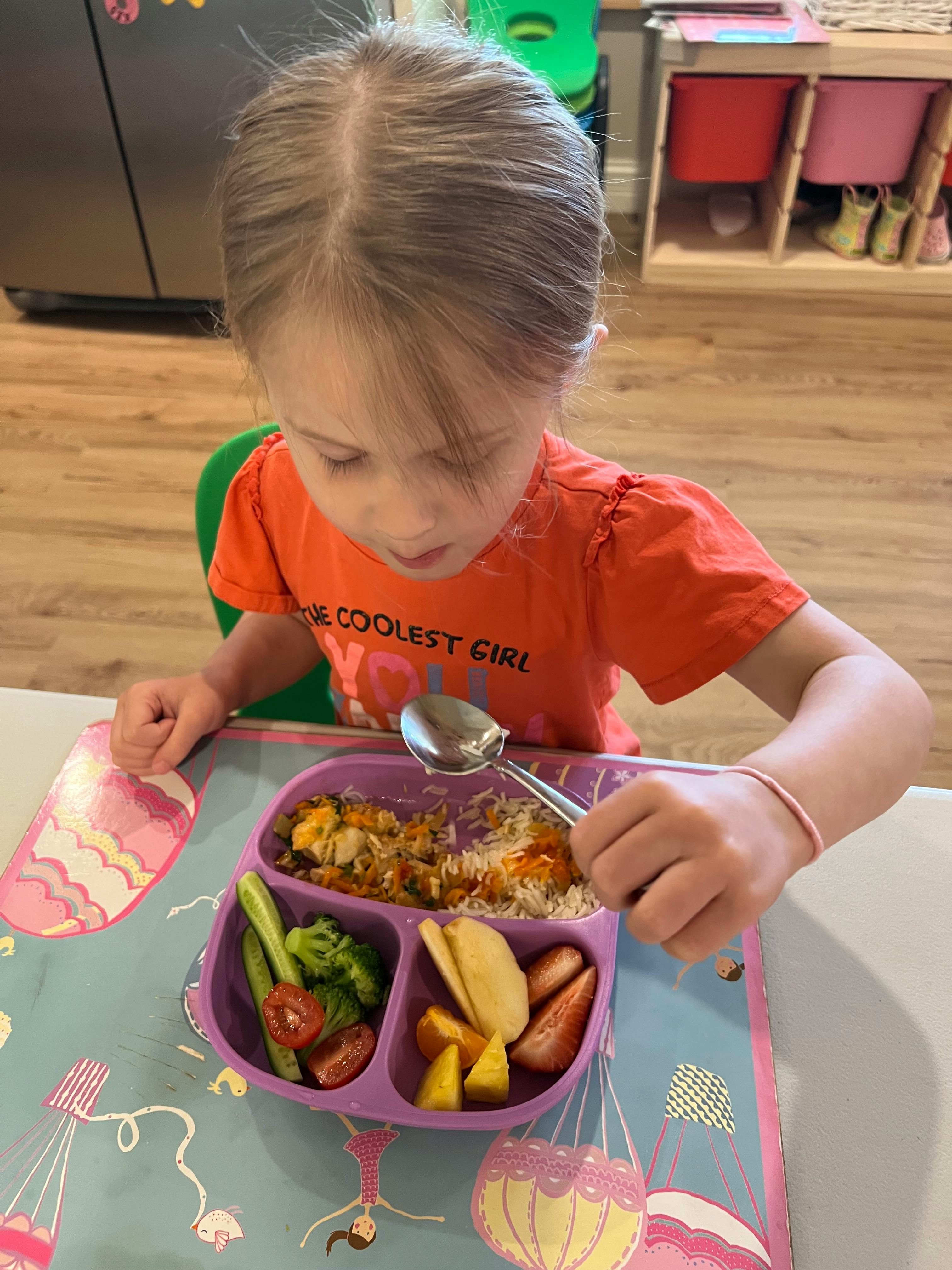 Child eating from a divided plate with a spoon