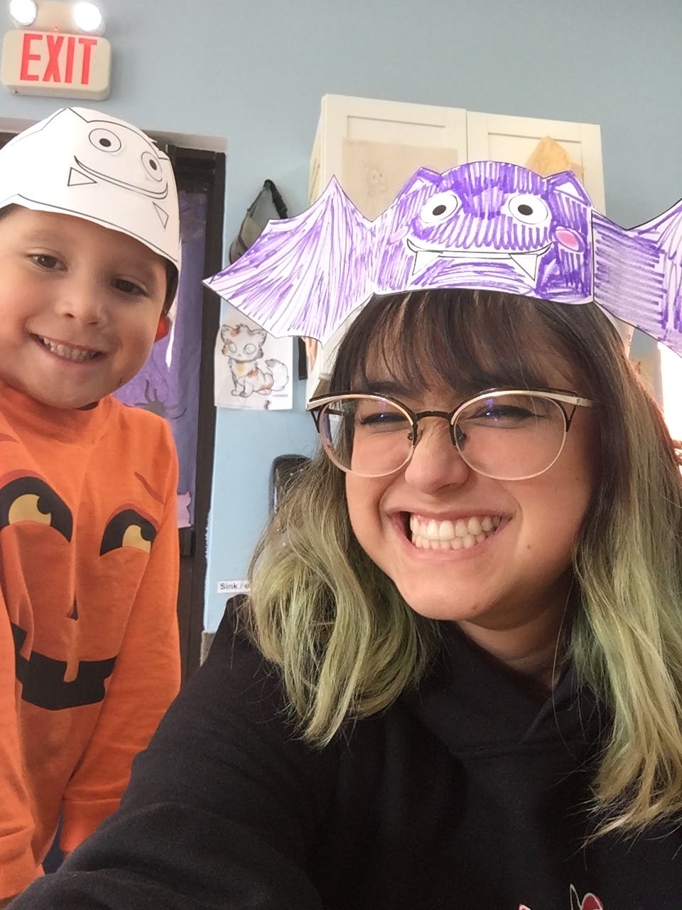 Person wearing a bat headband and child in a pumpkin shirt