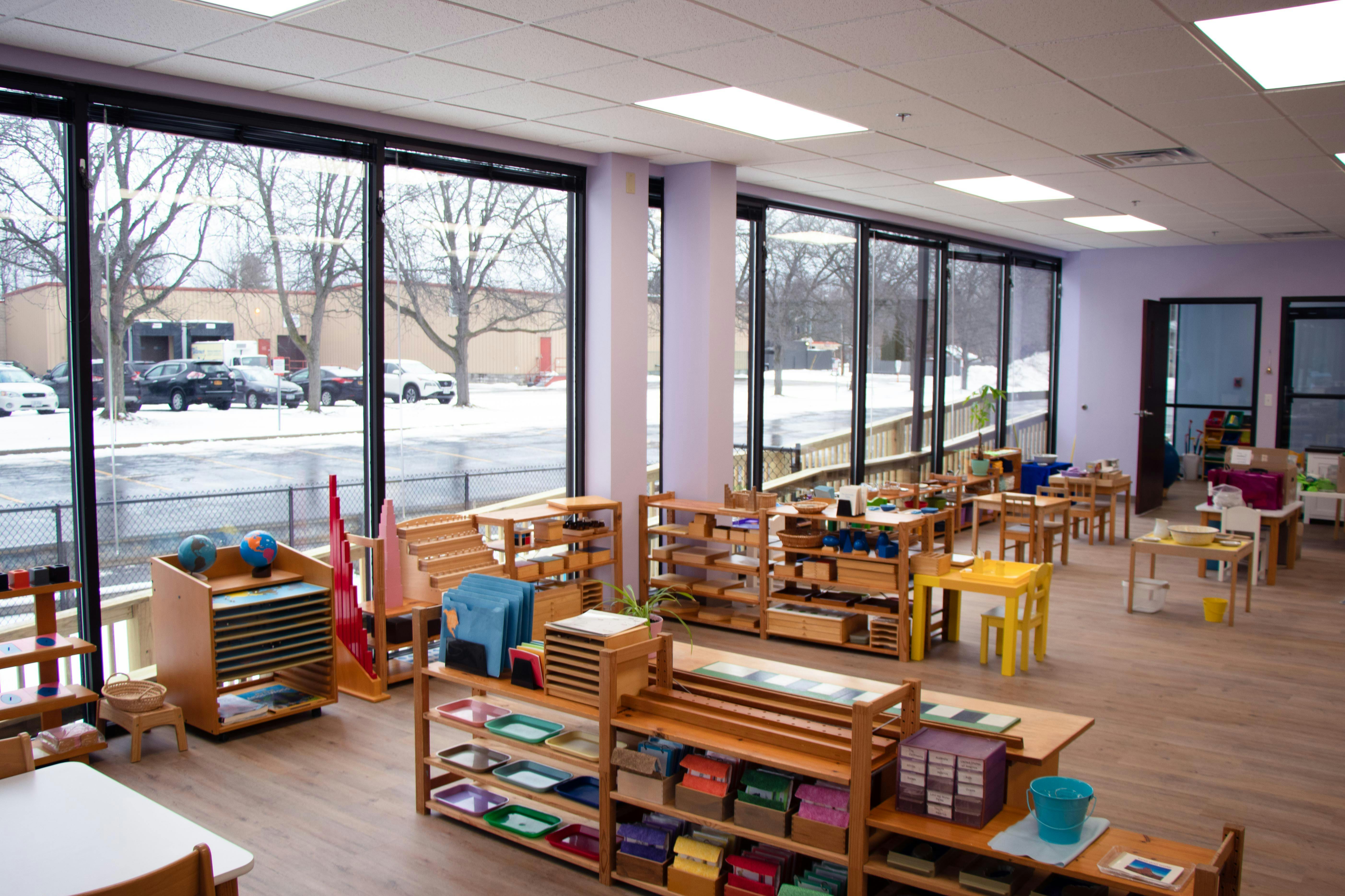 Classroom with wooden shelves, tables, and large windows overlooking a snowy landscape
