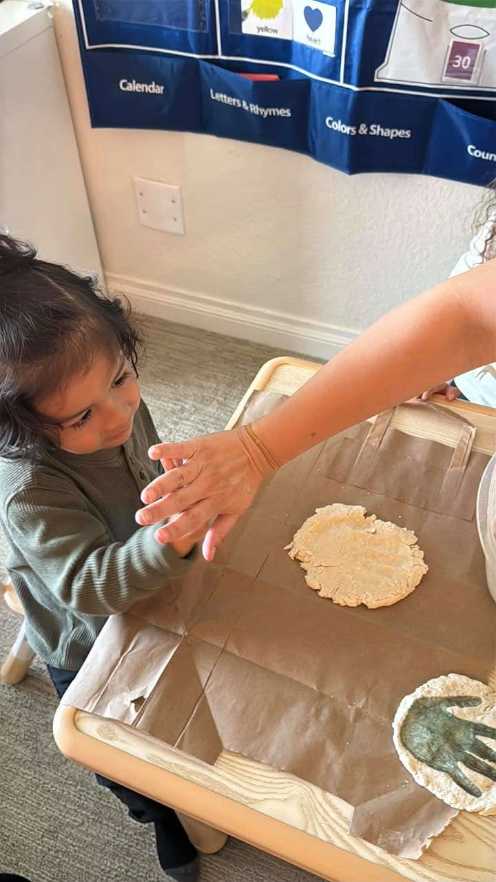 Child and person making handprints in dough