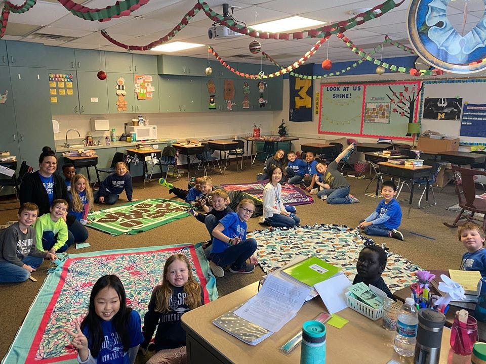 Children and an adult sitting on blankets in a classroom