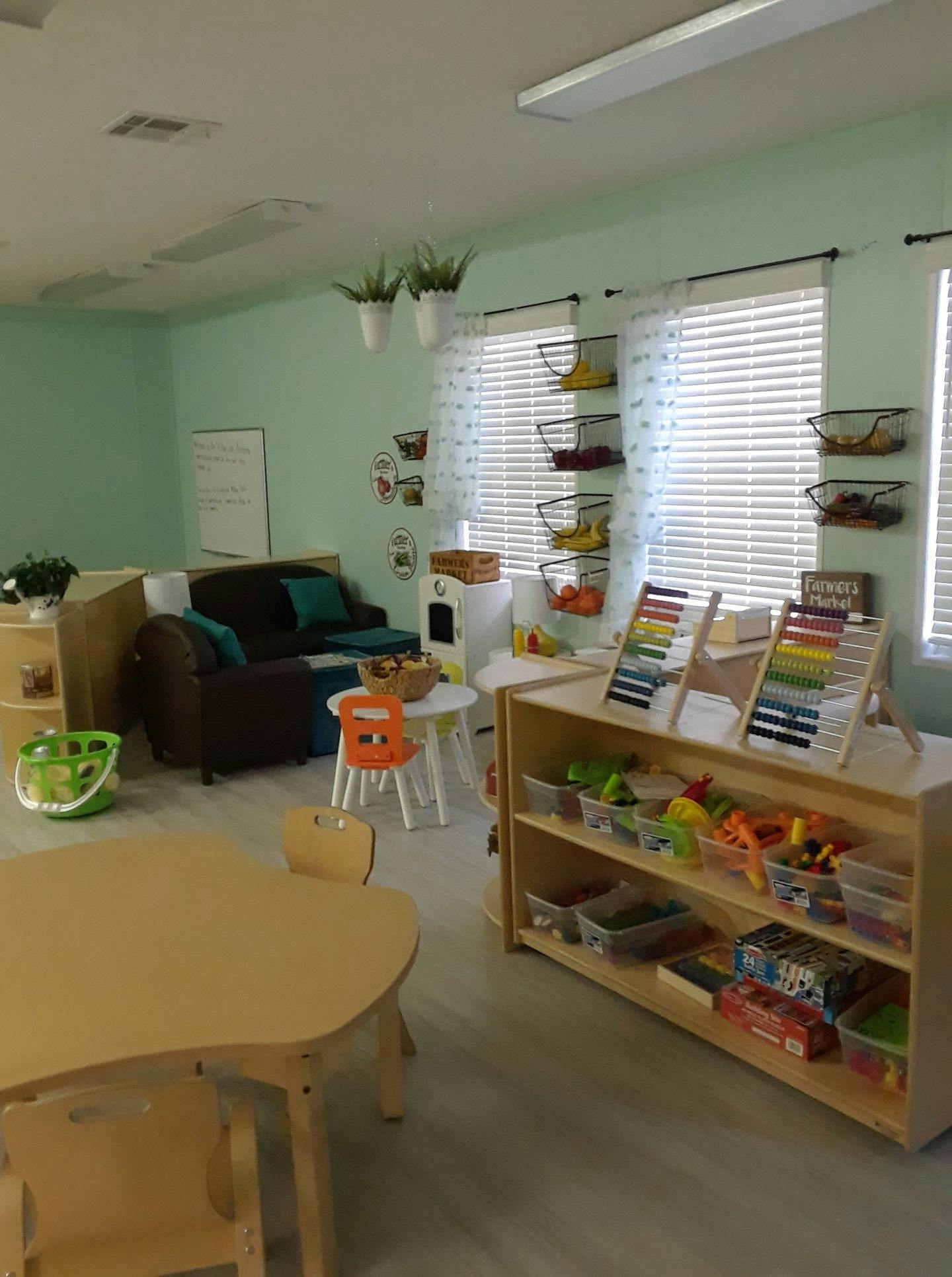 Classroom with small tables, chairs, and shelves of toys