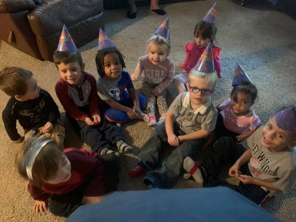 Group of children wearing party hats sitting on the floor