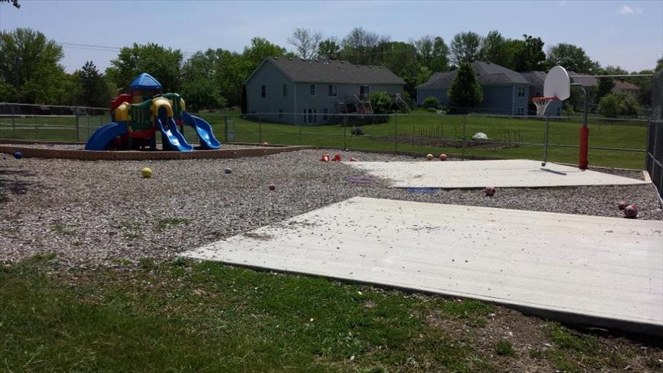 A colorful playground set and a basketball hoop on a sunny day