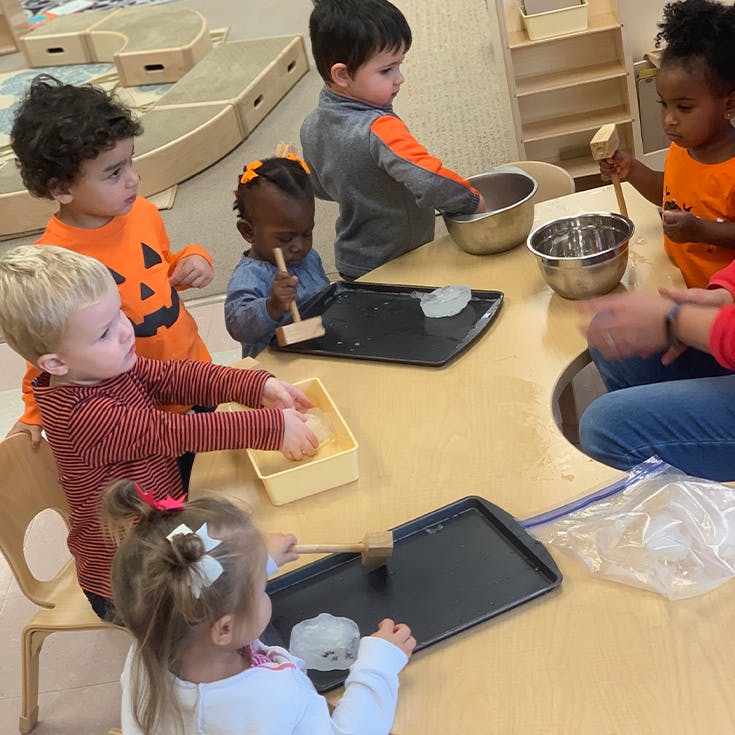 Children at a table playing with ice and mallets