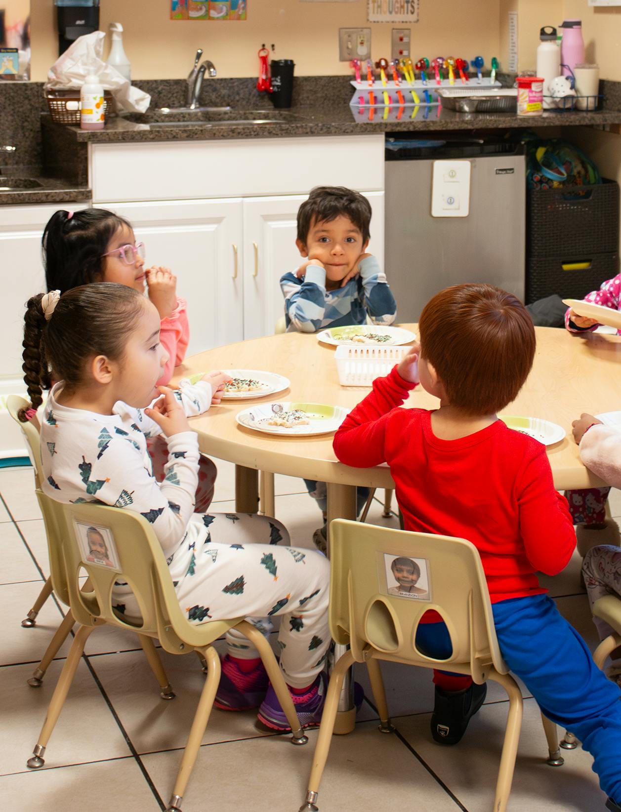 Children sitting at a round table, some with plates of cookies