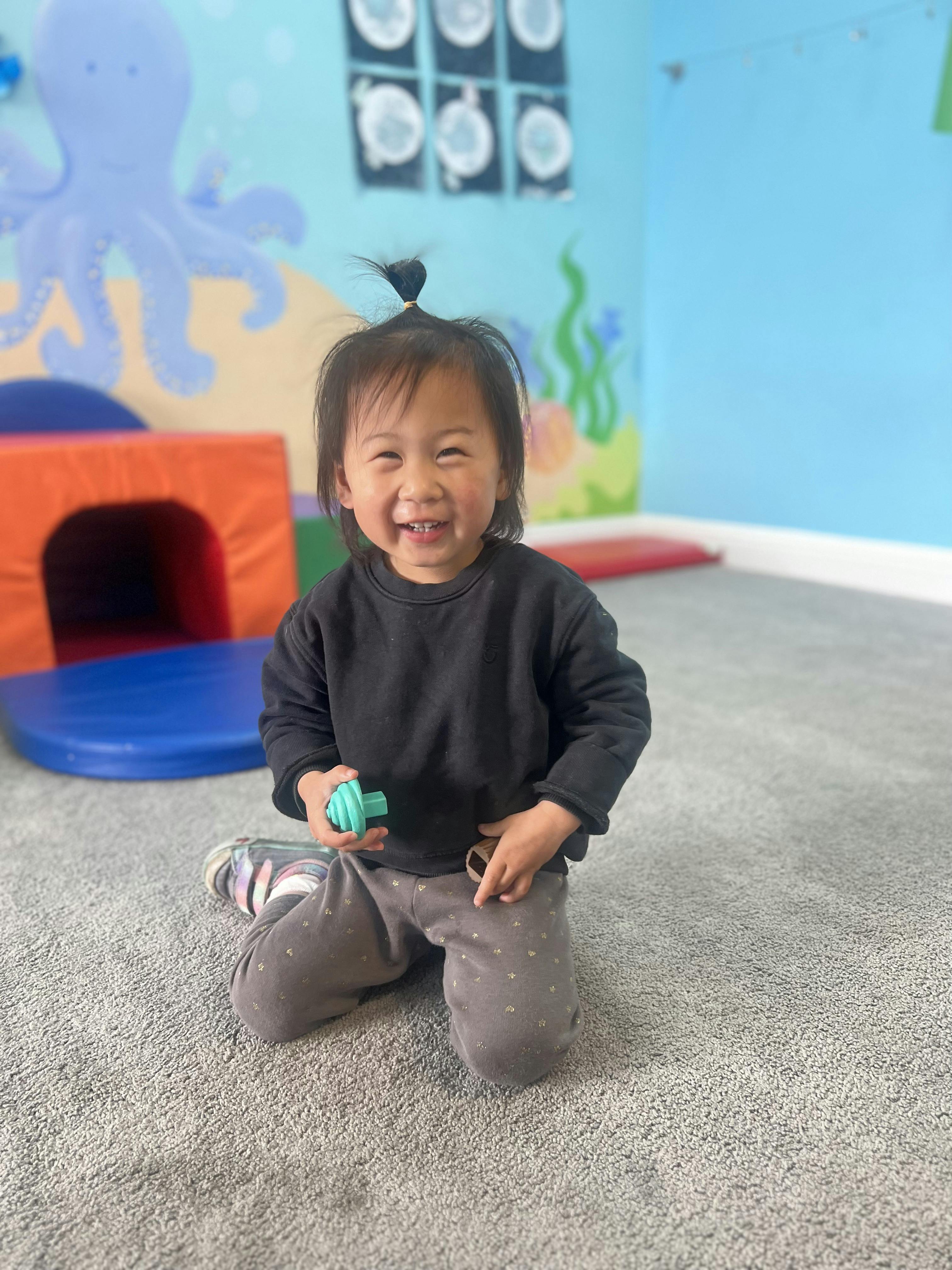 Child kneeling on carpet in a play area