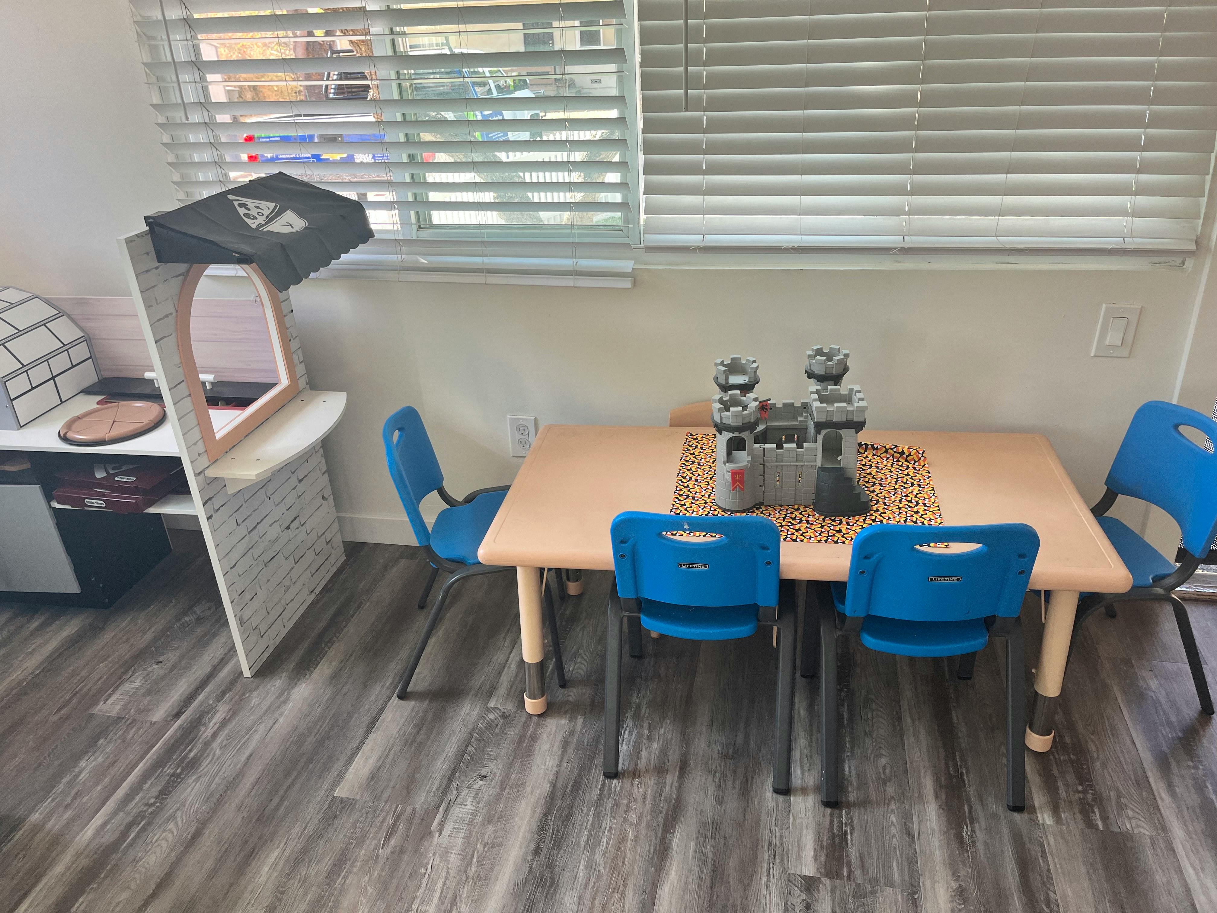 Small table with four blue chairs and a toy castle