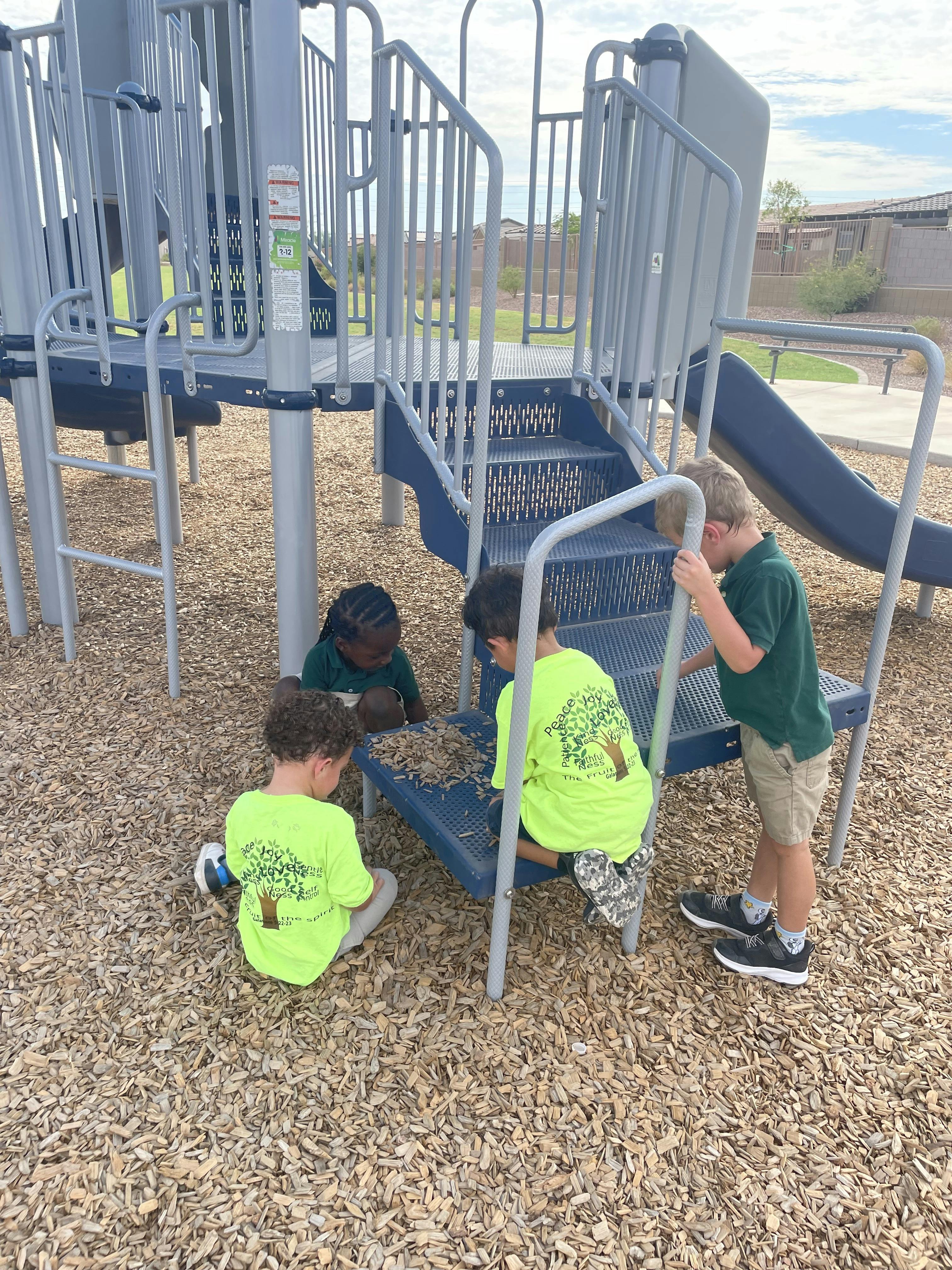 Children playing with wood chips on a playground structure