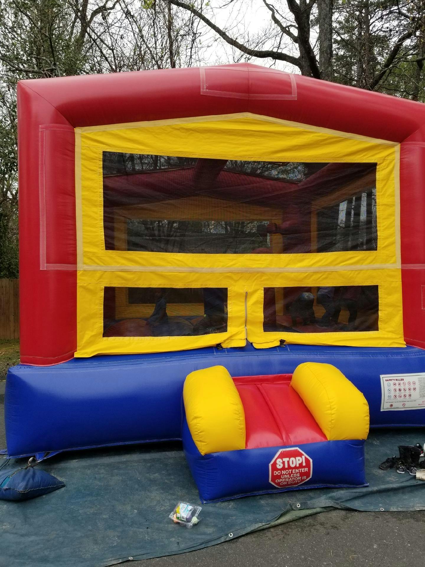 Red and yellow bounce house with a small inflatable chair in front