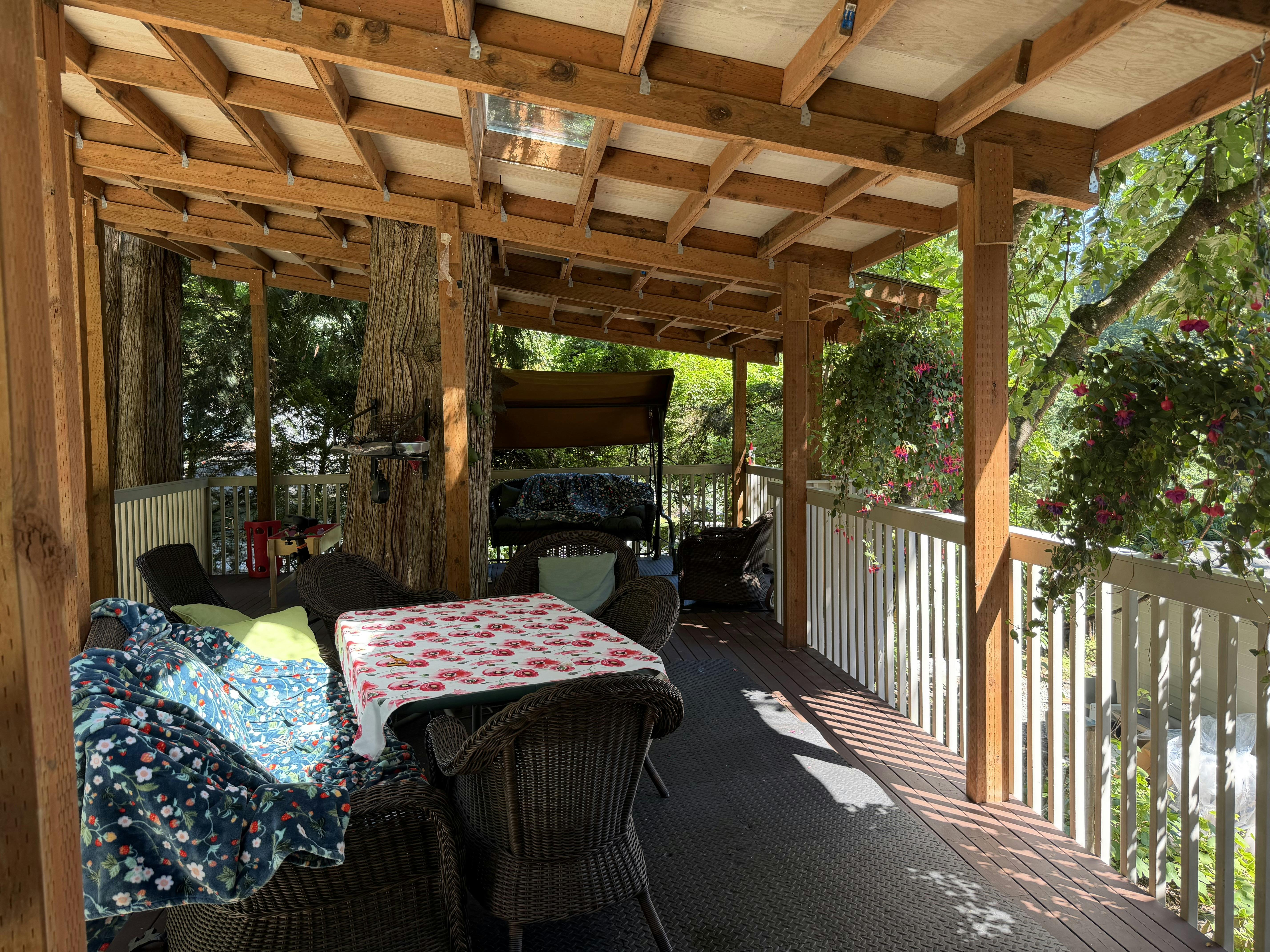 Covered wooden deck with wicker furniture and a table