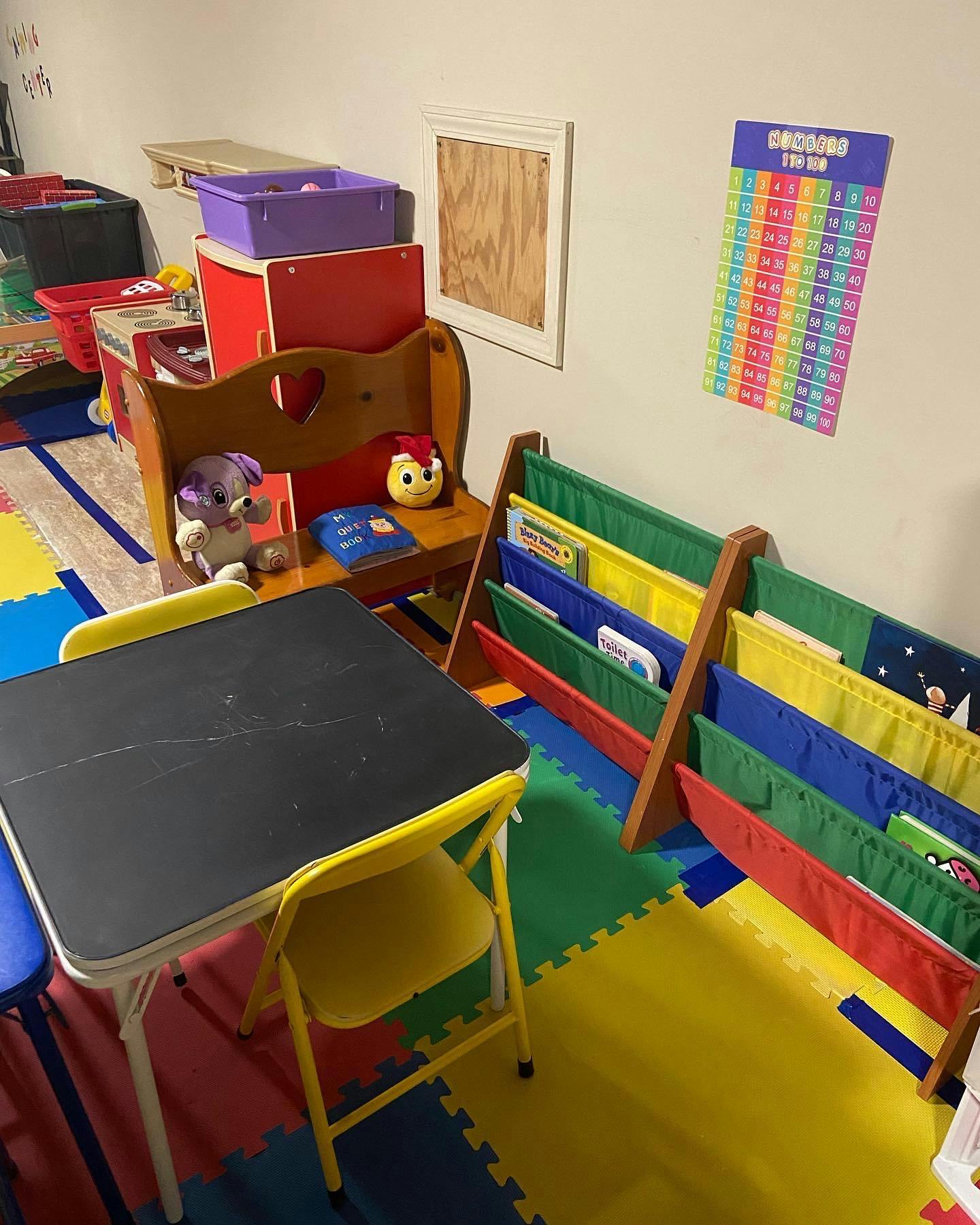 Children's play area with small table and chairs, toy shelf, and book display