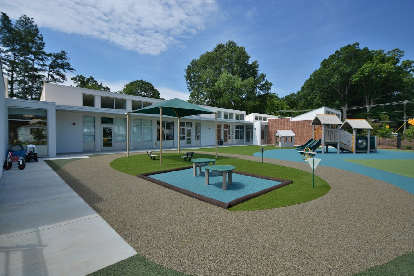 Outdoor playground area with buildings, green spaces, and play structures