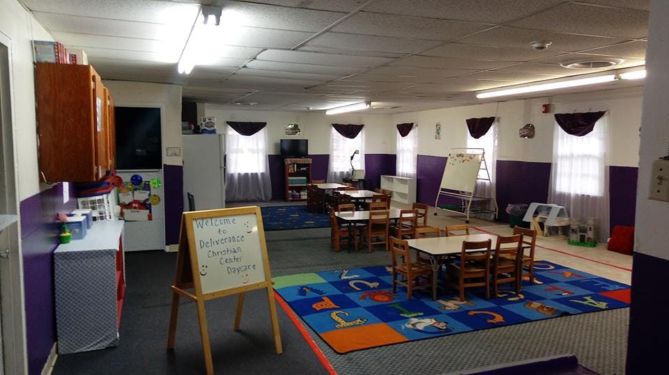 Classroom with small tables and chairs, alphabet rug, and whiteboard