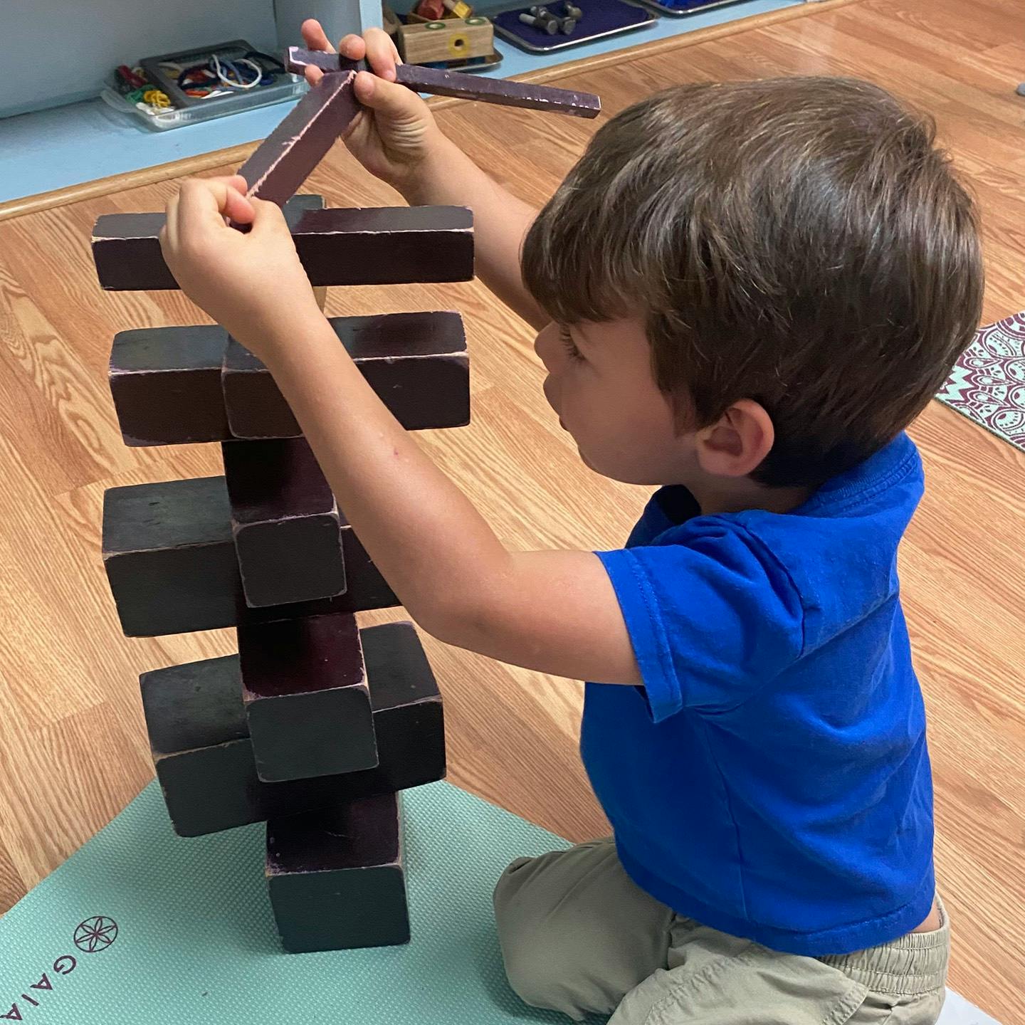 Child building a tower with dark wooden blocks