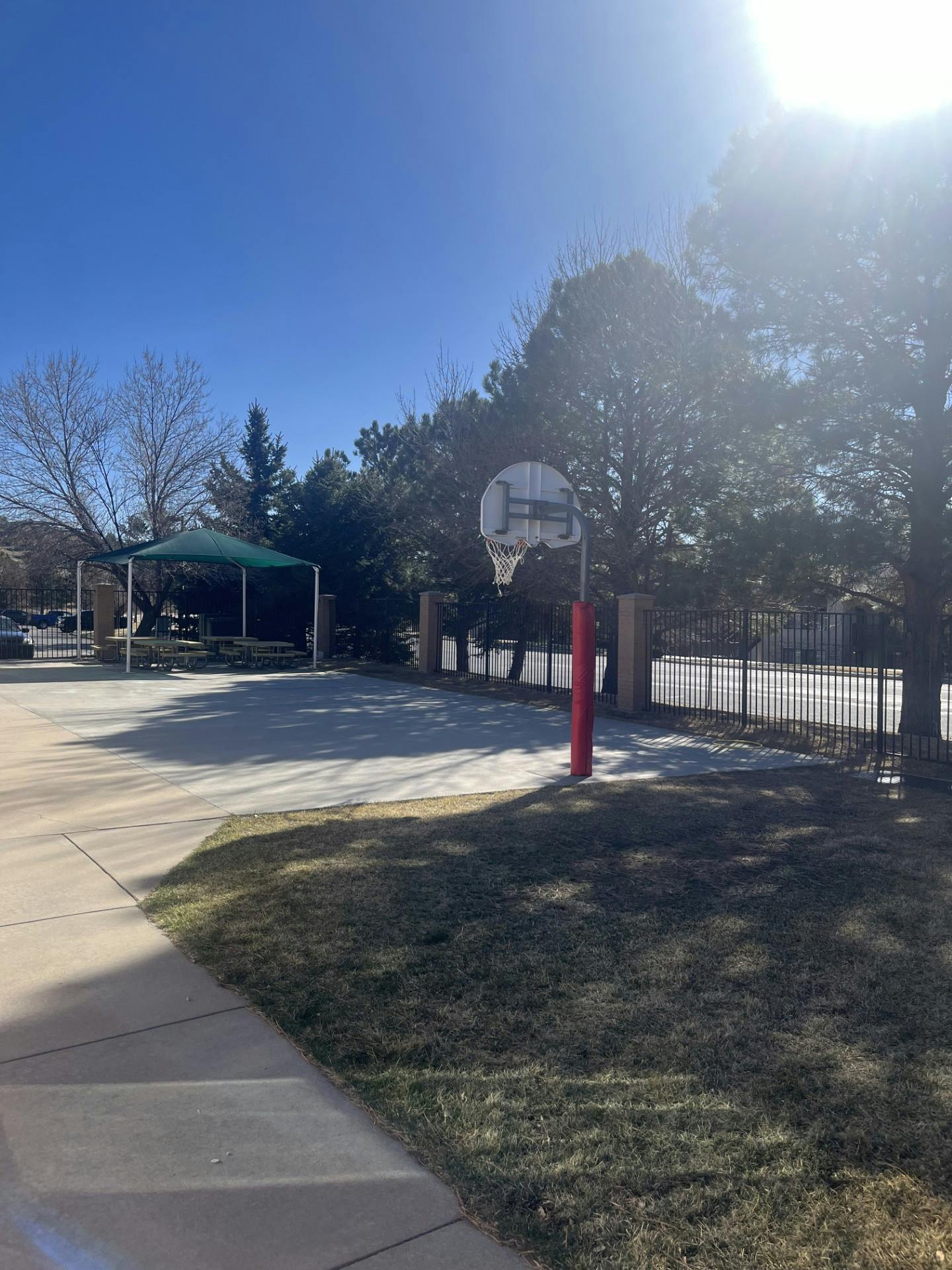 Basketball hoop on a court next to a shaded picnic area