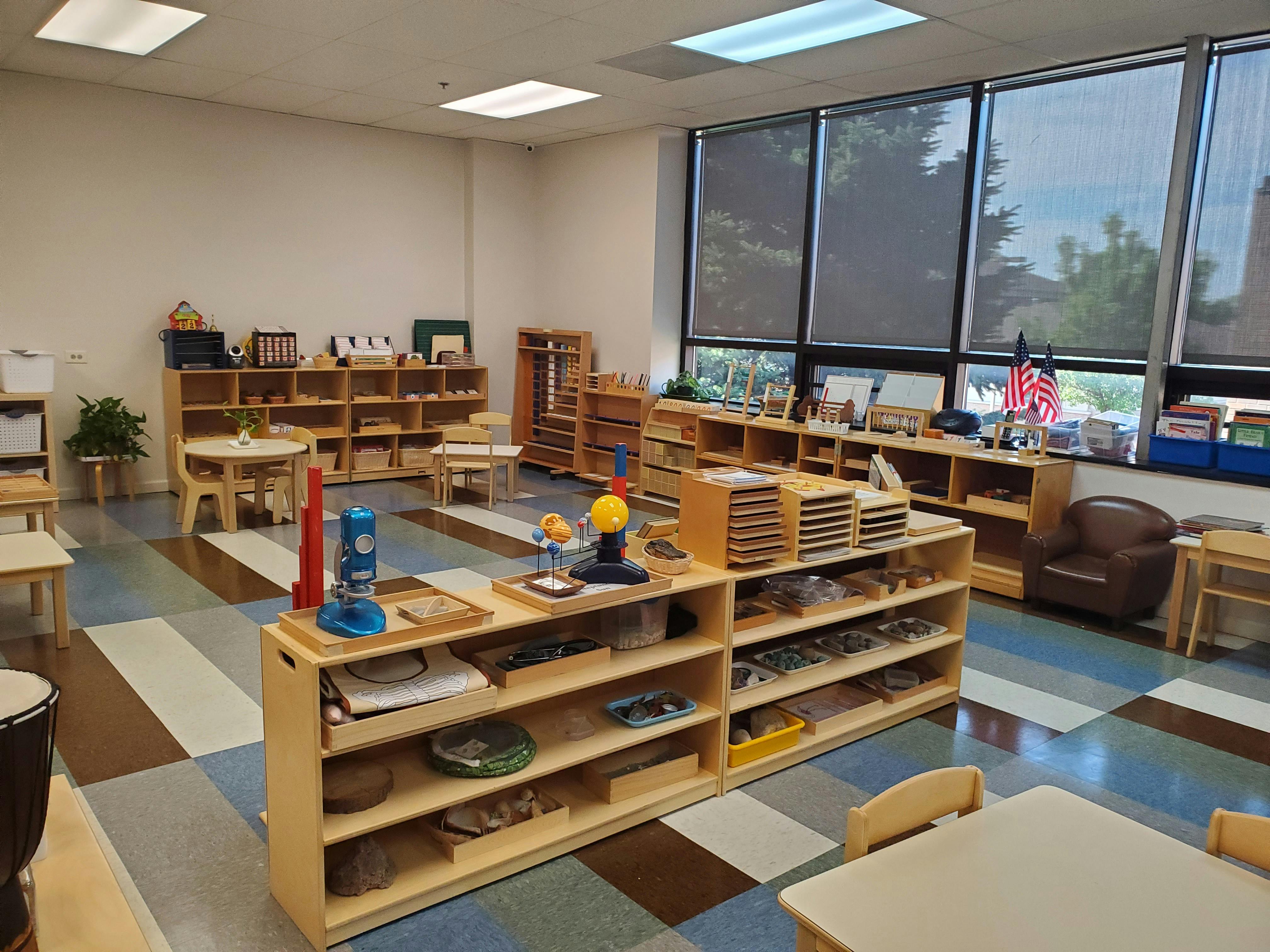 Classroom with wooden shelves, tables, and chairs