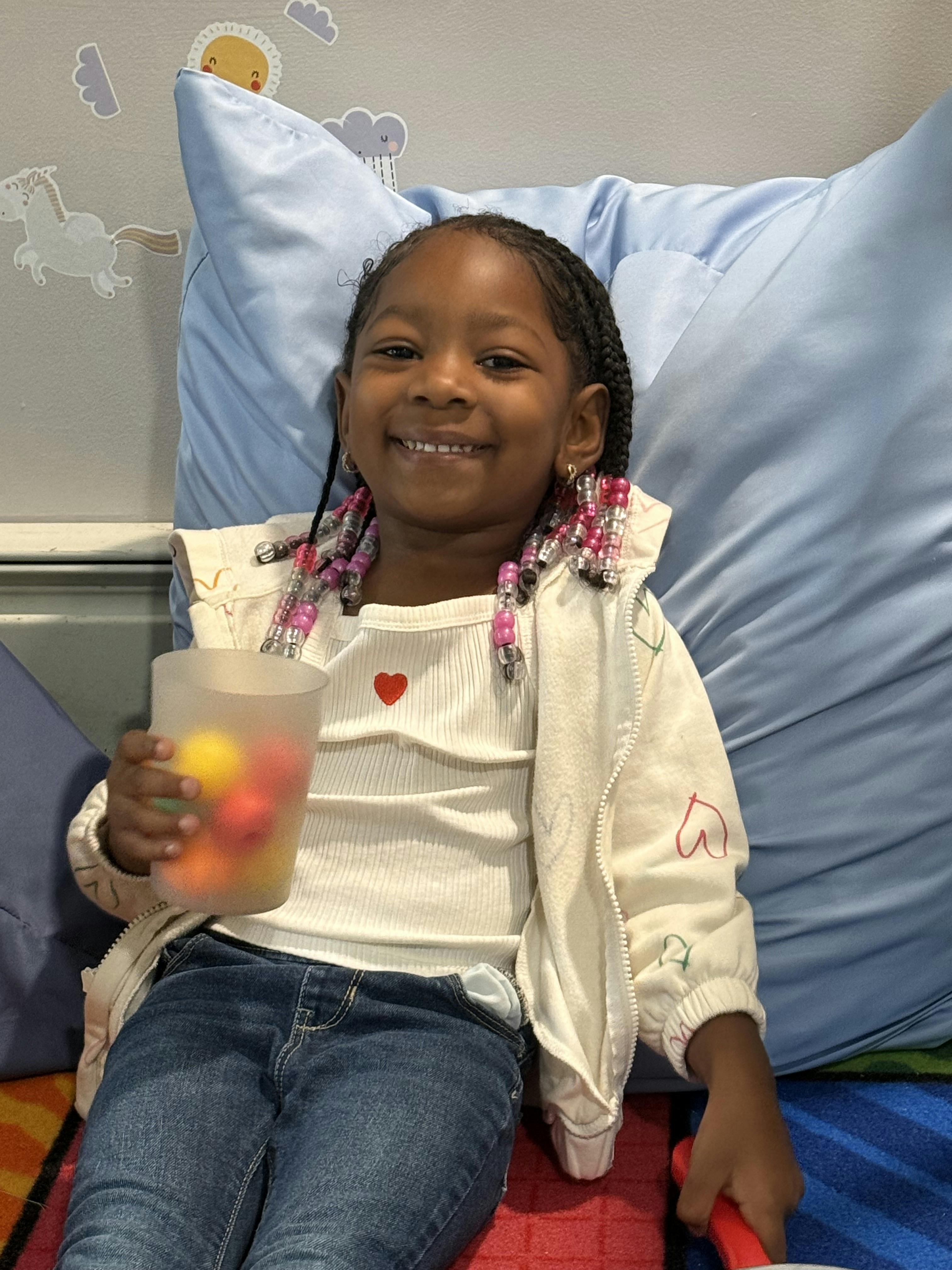 Child holding a cup with colorful items