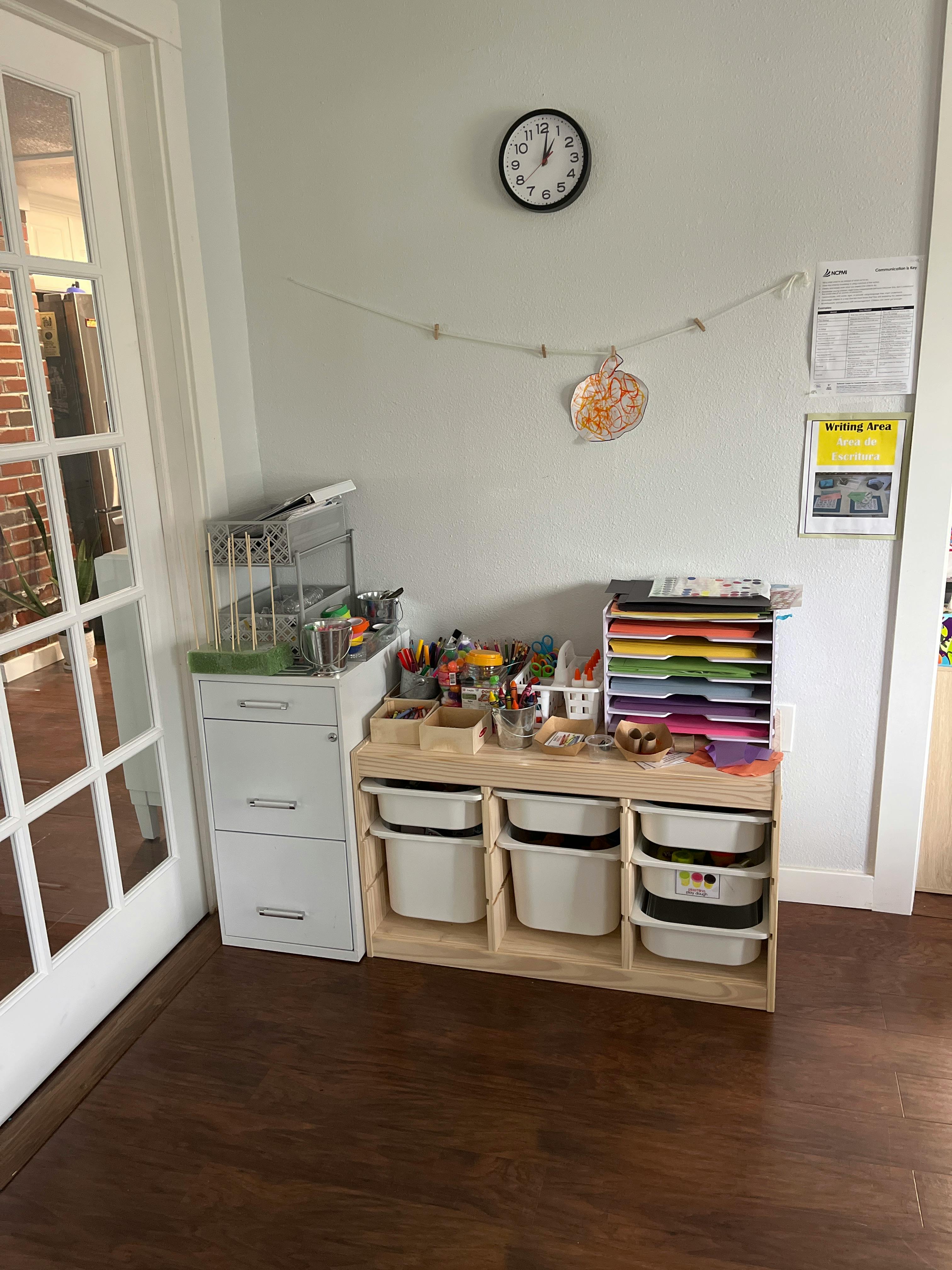 Craft supplies and storage bins in a room with a clock on the wall