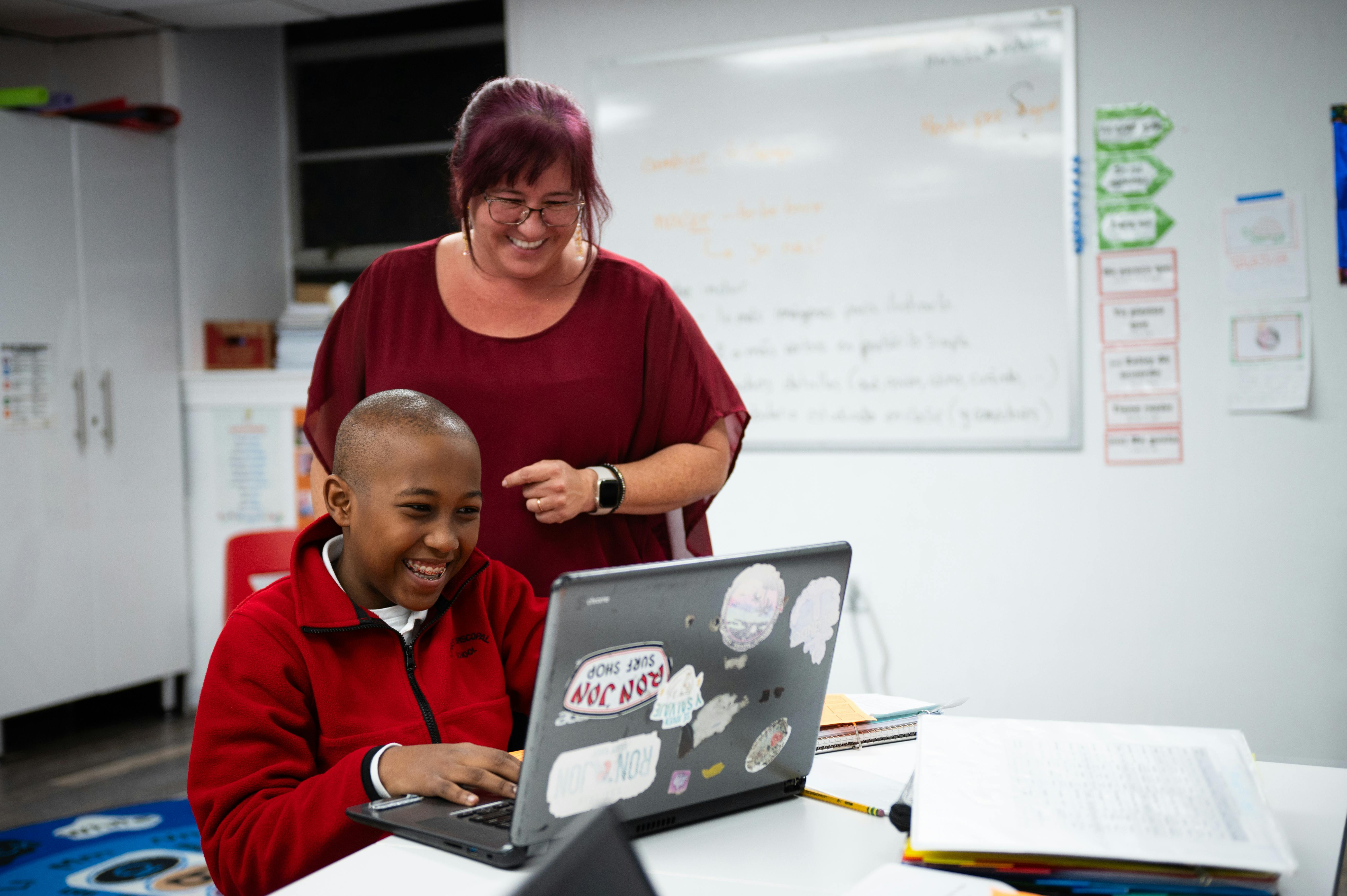 Adult and child looking at a laptop in a classroom