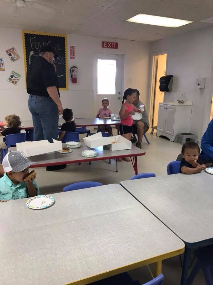 Adult and children in a classroom eating at tables